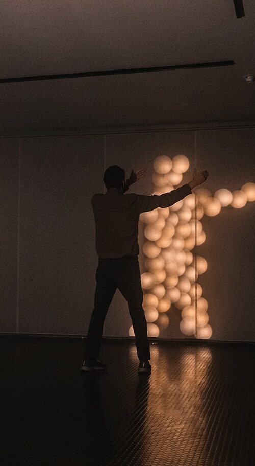 A person interacting with Brandon Lattu's Reciprocity of Light artwork.